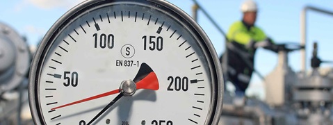 A pressure gauge displays the pressure, with a needle pointing to around 50. Industrial equipment is visible in the background.